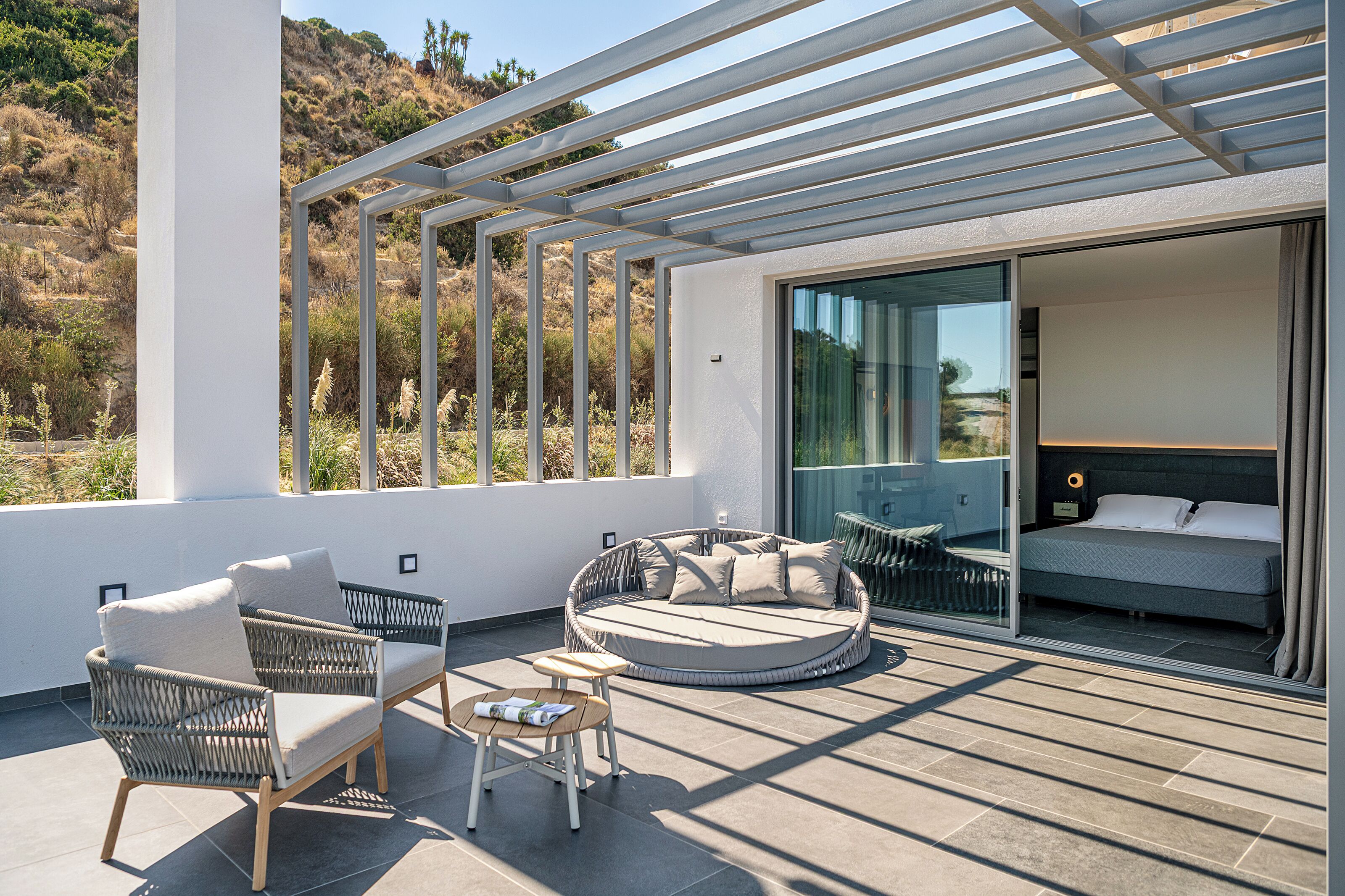 Eine moderne Außenpatio mit Korbmöbeln, einer runden Sitzecke und einem Bett mit Blick.