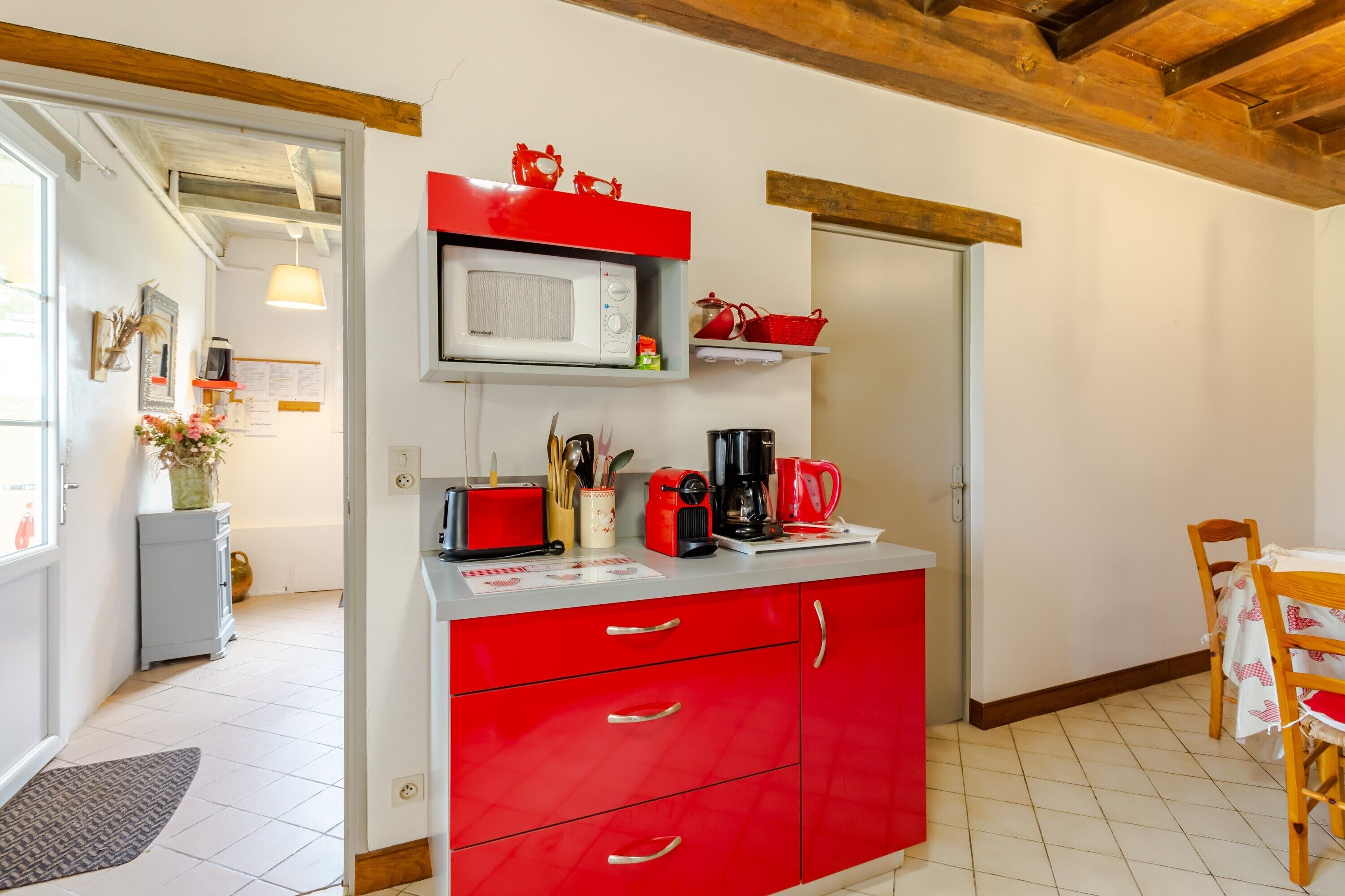 Una cucina con mobili rossi, un forno a microonde, una macchina da caffè e un tostapane rosso.