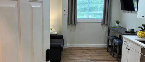 A modern kitchen with a wooden floor, a dining area with a table and chairs, and a TV mounted on the wall.