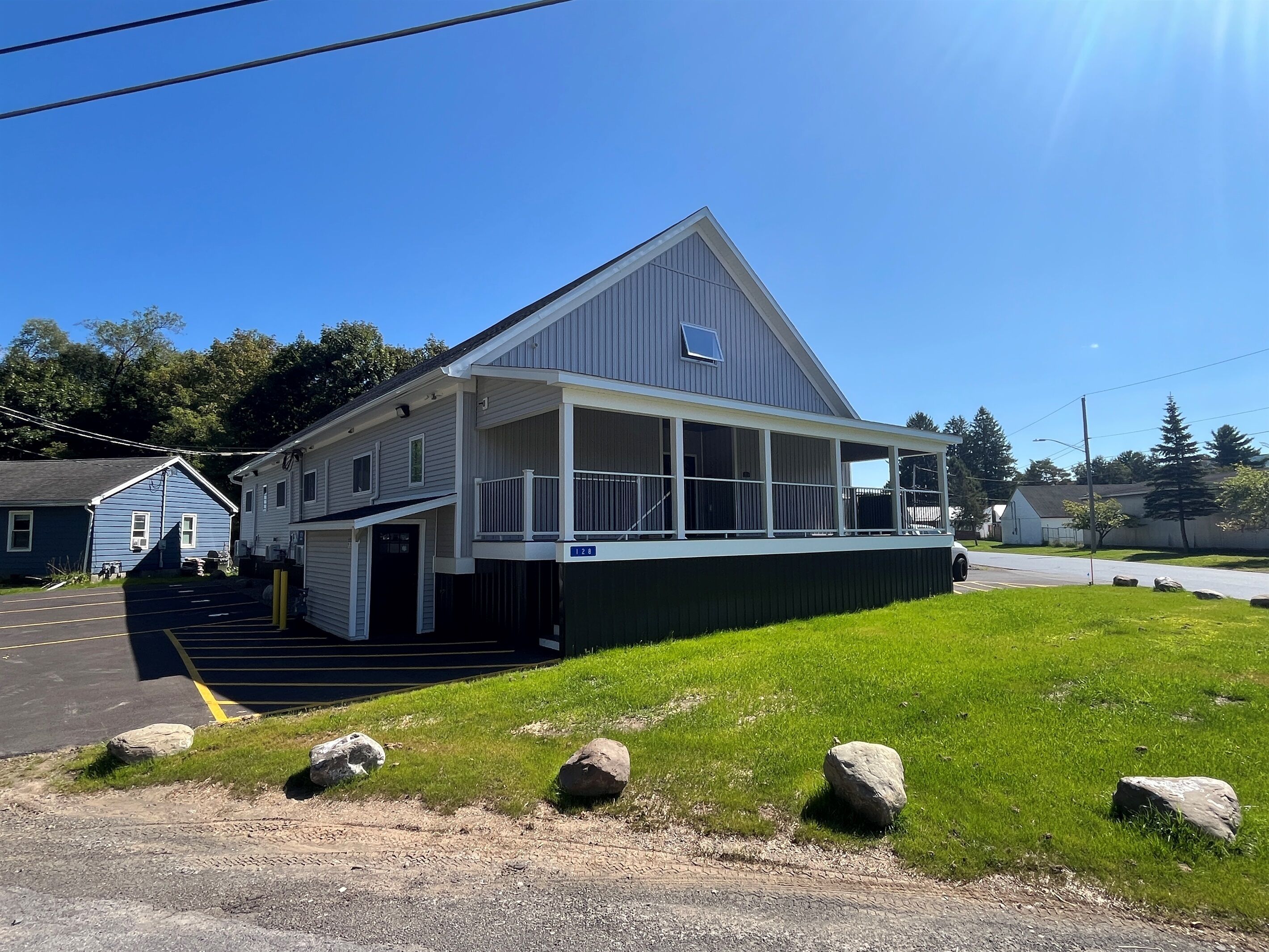 A two-story building with a covered porch and a small balcony.