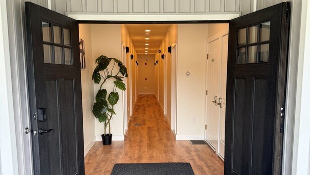 A hallway with a wooden floor, a black mat at the entrance, and a potted plant on the left. - Winney Hill Studios #5 of 8 Studios - Full Renovation, 1 mile to ASV (Oneonta)