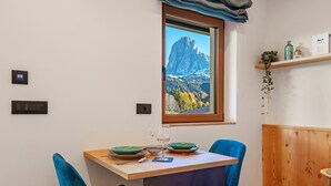 Ein Essbereich mit Tisch, Stühlen und einem Fenster mit Blick auf die Berge.