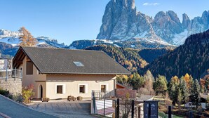 Eine Berglodge mit einem geneigten Dach, einer Steintreppe und Blick auf zerklüftete Berge.