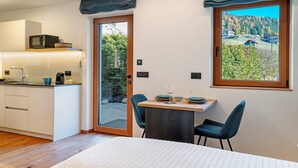 Eine moderne Küche mit Mikrowelle, ein Essbereich mit Tisch und Stühlen sowie ein großes Fenster mit Blick auf eine bewaldete Landschaft.