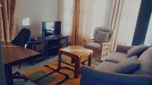 A living room with a sofa, a coffee table, a TV, and a desk.