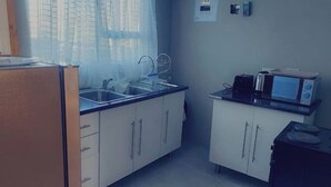 A compact kitchen with a sink, microwave, and cabinets.