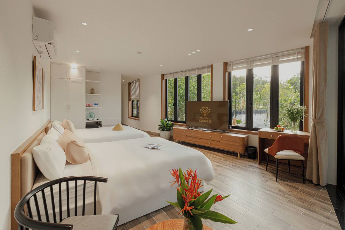 Une chambre d’hôtel moderne dotée d’un grand lit, d’un bureau, d’une télévision et offrant une vue sur la verdure.