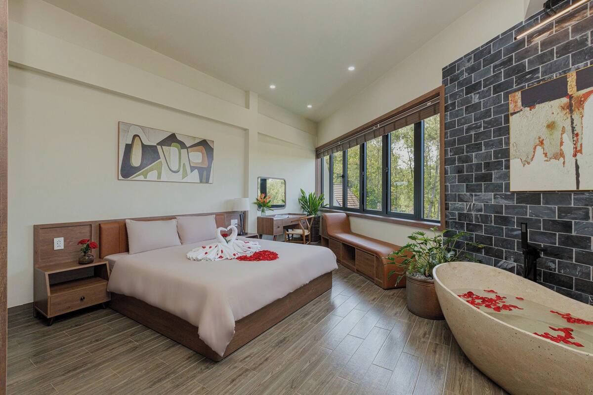 Une chambre à coucher moderne avec un grand lit, une banquette intégrée, une baignoire et un coin bureau.