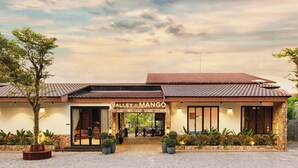 A building with a sign reading "Valley of Mango" and a paved entrance area with potted plants. - VALLEY DE MANGO VILLA (Hue)