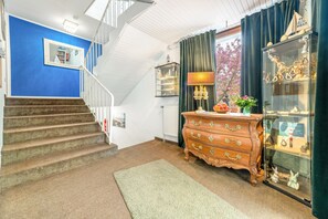 Eine Treppe führt zu einer Empore mit einer blauen Wand und einer Holzkommode mit Schubladen.