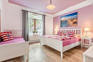A bedroom with a bed, bedside tables, a window with curtains, a painting on the wall, and a hanging light fixture. - Apartment '1' with Modern Country-Style Kitchen (Cuxhaven)