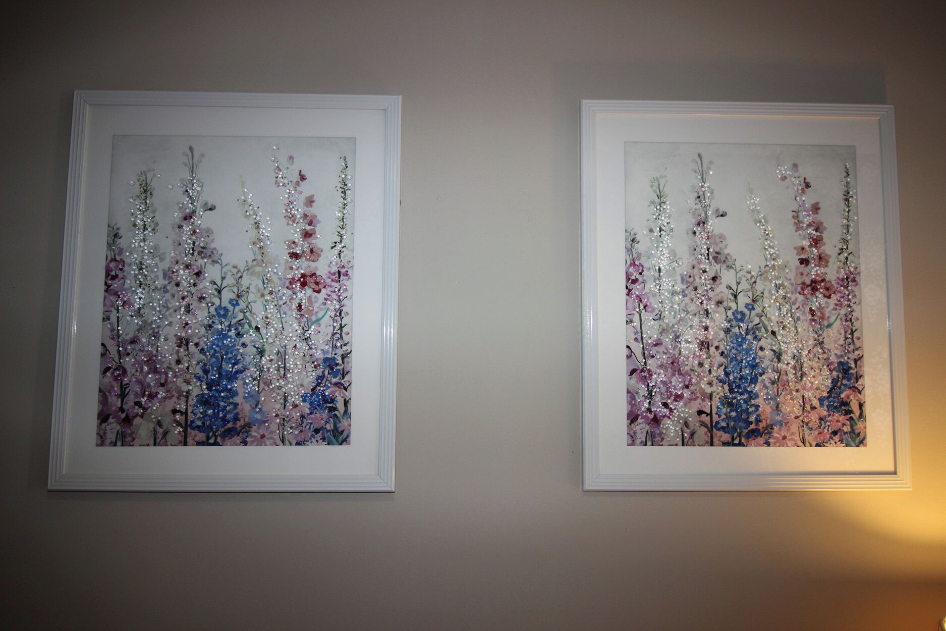 Two framed floral artworks on a plain wall.