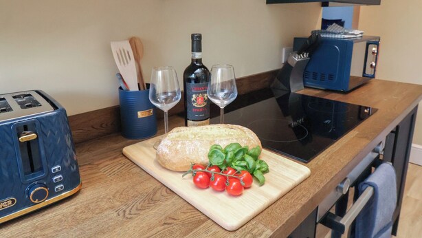 Ett kök med en brödrost, en flaska Chianti Riserva-vin, två glas, ett bröd och tomater på en skärbräda.