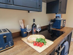 A kitchen with a toaster, a bottle of Chianti Riserva wine, two glasses, a loaf of bread, and tomatoes on a cutting board. - Blackburn Heights Apartment 2 (Bridlington)