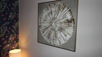 A framed artwork on a wall, a lamp, and a floral wallpaper pattern.