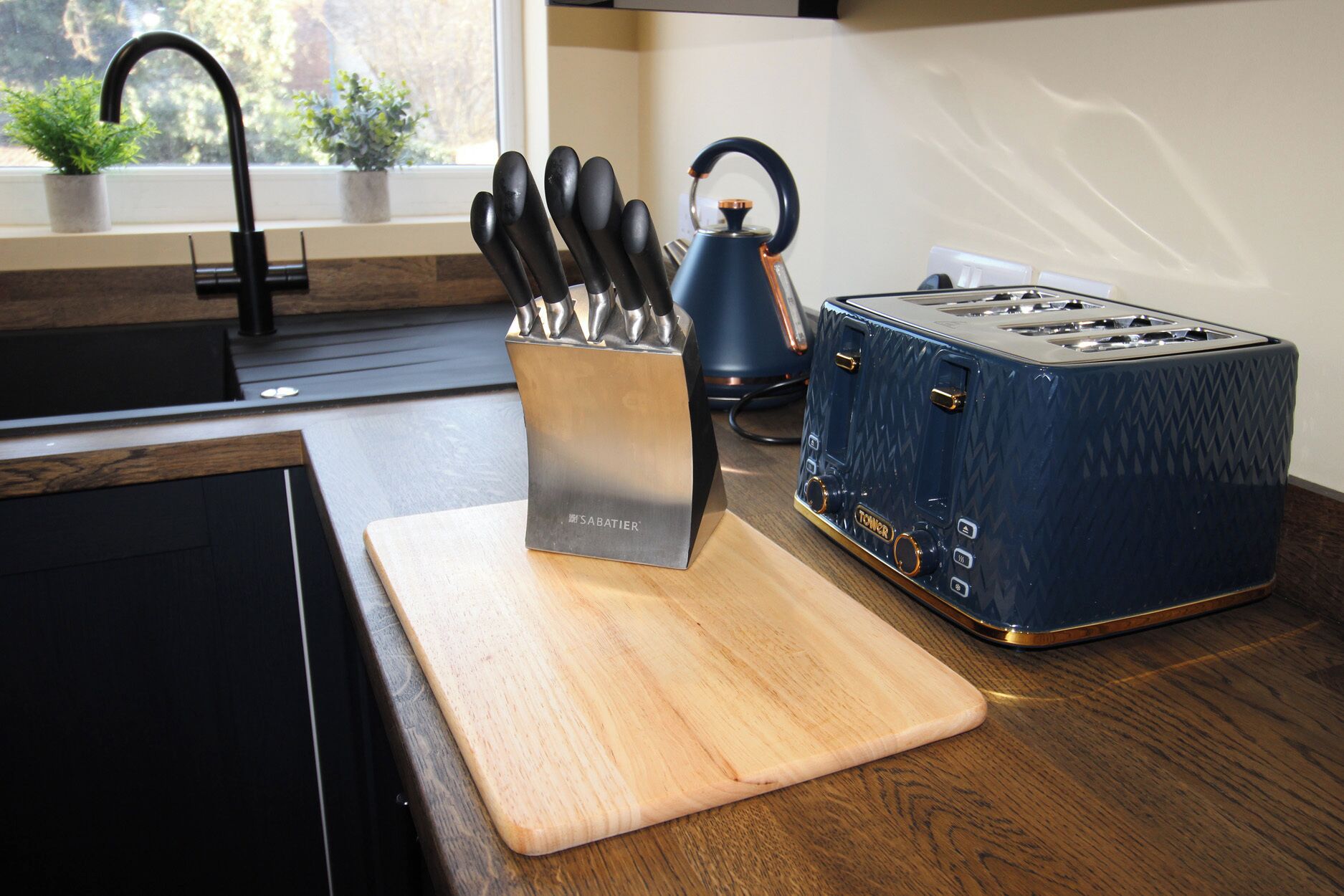 A kitchen counter with a toaster, a knife block, and a kettle.