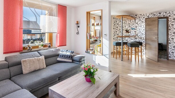 Una sala moderna con un sofá gris, una mesa de centro de madera y una cortina roja.