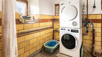 A laundry room with a washing machine and dryer, a window with a view, and a tiled wall.