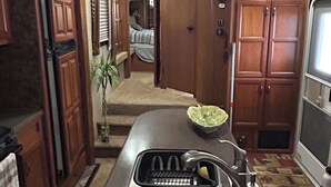 Cucina compatta con lavello in acciaio inossidabile, mobili in legno e ventilatore a soffitto.