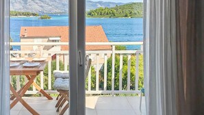 Een balkon met een tafel en stoelen, met uitzicht op een meer en bergen op de achtergrond.