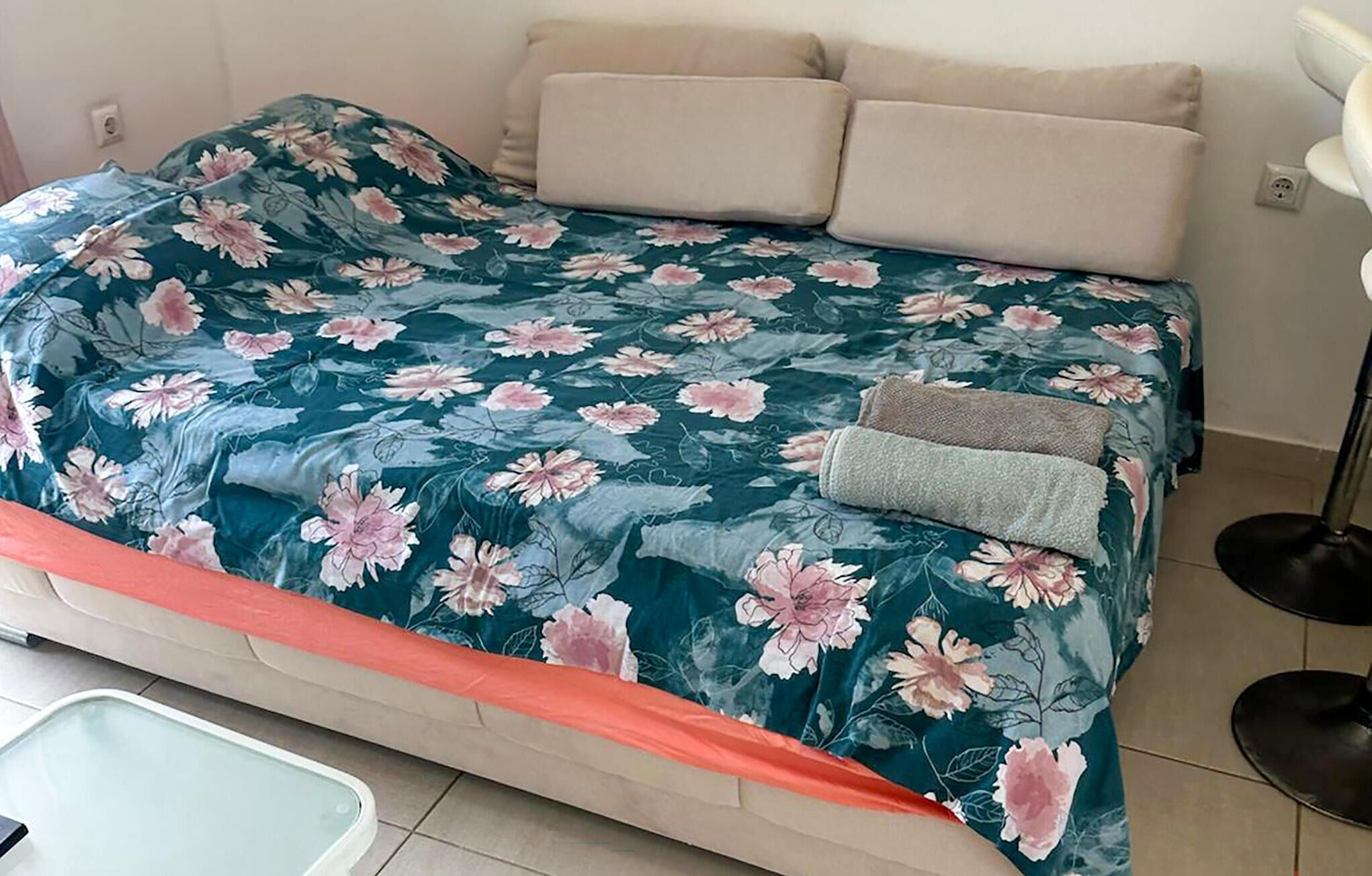 A bed with a floral bedspread, two pillows, and a blanket.