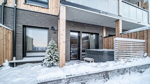 Moderni rakennus, jossa on tiiliverhous, suuret ikkunat ja puinen terassi.