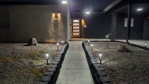 Un chemin menant à l’entrée d’un bâtiment, avec le numéro « 816 » illuminé sur le mur.