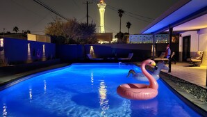 Une piscine avec un flotteur en forme de flamant rose, une vue sur une tour et des chaises longues.