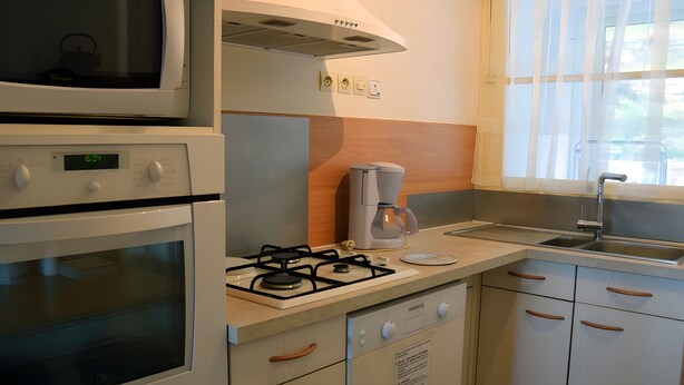 Een keuken met een fornuis, magnetron, oven en koffiezetapparaat.