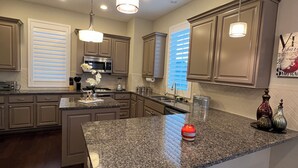 A modern kitchen with granite countertops, stainless steel appliances, and pendant lighting. - Modern Upscale 3-bedroom house in Houston energy corridor (Houston)
