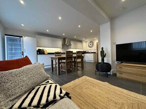 A modern living room with a sofa, a TV, and a dining area with chairs and a table. - Contractor &Leisure stay.4BR all en-suite +Parking (Portsmouth)