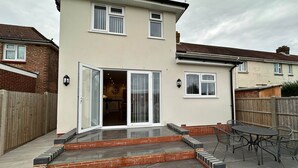 A two-story house with a patio, a sliding glass door leading to a kitchen, and a small outdoor seating area. - Contractor &Leisure stay.4BR all en-suite +Parking (Portsmouth)