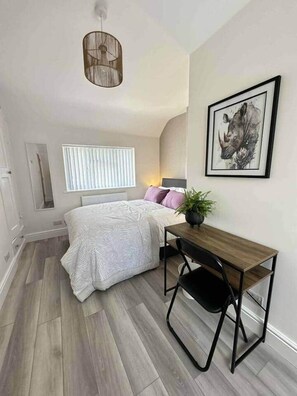 A bedroom with a bed, a desk, a chair, a window with blinds, a wall-mounted picture, and a hanging light fixture. - Contractor &Leisure stay.4BR all en-suite +Parking (Portsmouth)