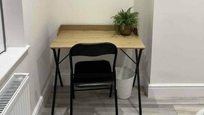 A small room with a wooden table, a black chair, a potted plant, and two framed pictures on the wall. - Contractor &Leisure stay.4BR all en-suite +Parking (Portsmouth)