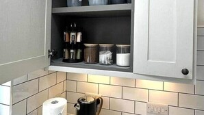 Une cuisine dotée d’un meuble intégré contenant de la vaisselle, des tasses et des boîtes de rangement.