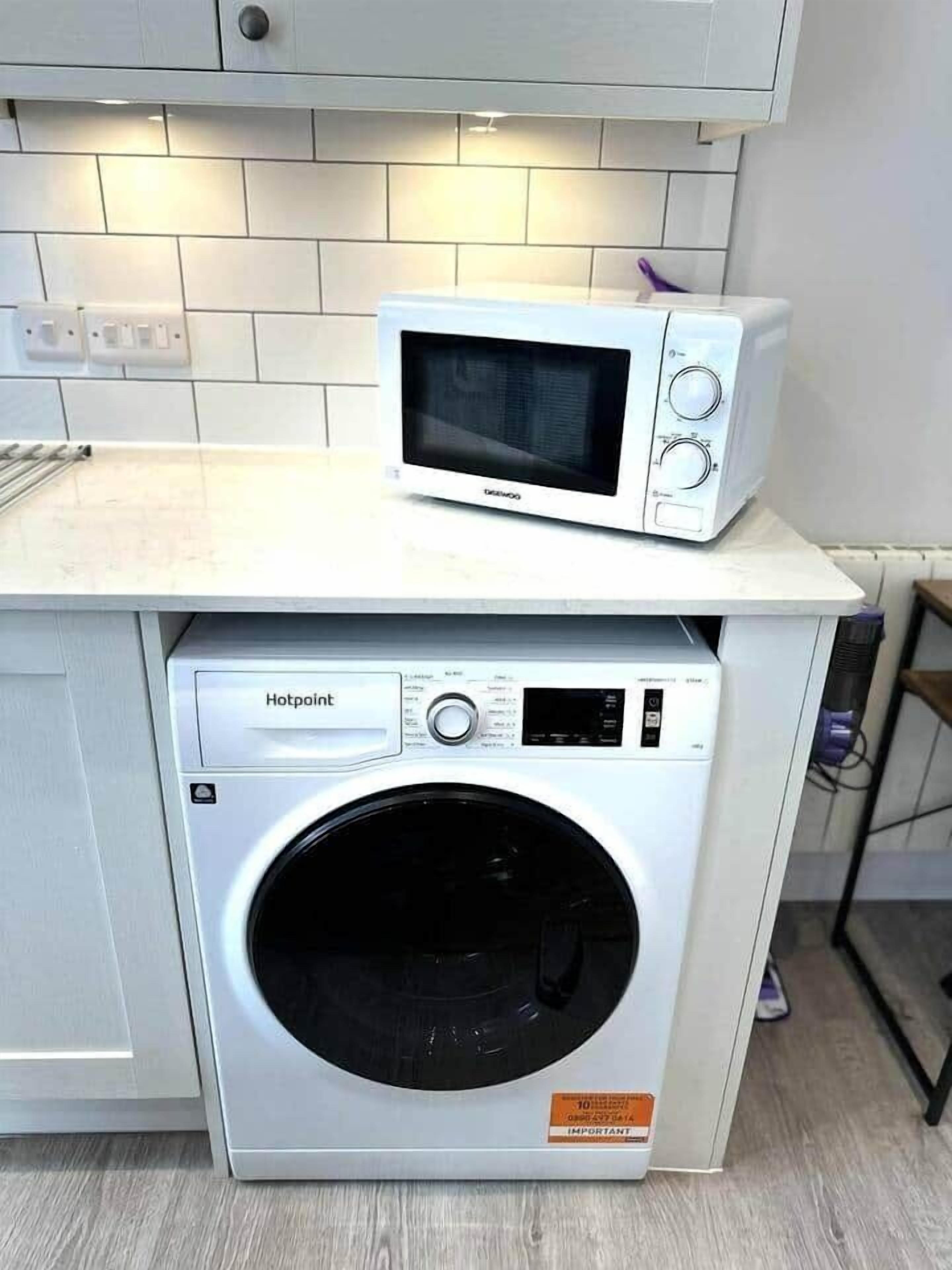 A compact kitchen with a microwave on top of a washing machine.