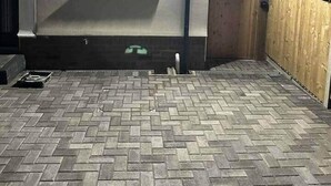 Un espace extérieur abrité, doté d’une fenêtre, d’un sol en briques et d’une clôture en bois.