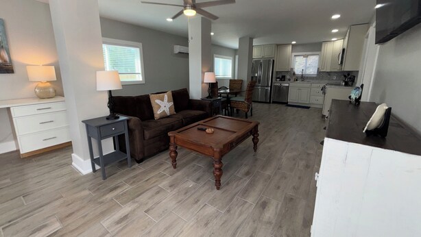 A modern living room with a brown sofa, a wooden coffee table, and a dining area with wicker chairs. - New -1st Floor Spacious Kit W&D Close 2 Everything 3Mi To Beach Sleeps 4 KingBed (Bonita Springs)