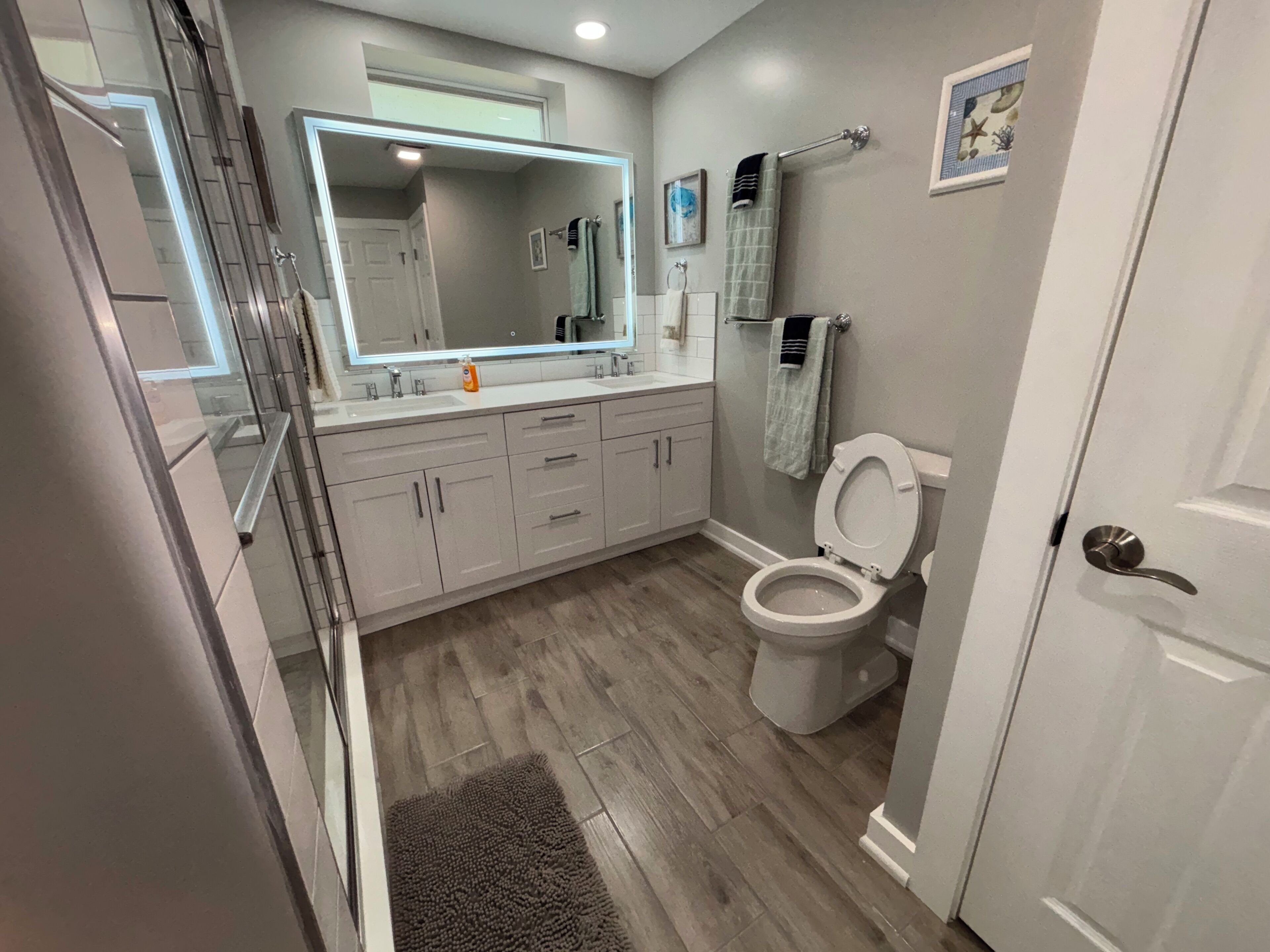A modern bathroom with a large mirror, a toilet, and a shower area.