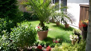 A garden with potted plants and flowers, a lawn, and a building with a window and door. - Holiday Home 'Blumenhof' with Shared Garden, Balcony and Wi-Fi (Wandlitz)