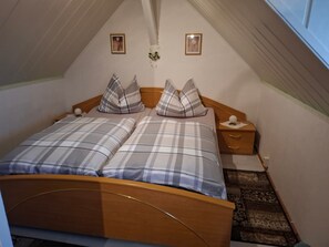 A bedroom with a bed, two bedside tables, a nightstand, a small decorative item, and a wall-mounted picture.