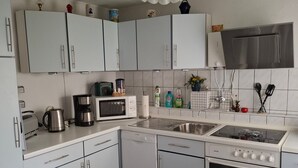 A modern kitchen with white cabinets, a microwave, a coffee maker, a dishwasher, a stove, and a sink. - Holiday Home 'Blumenhof' with Shared Garden, Balcony and Wi-Fi (Wandlitz)