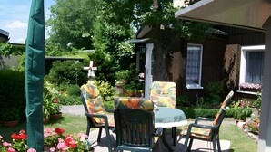 An outdoor patio with a table and chairs, surrounded by potted plants and flowers. - Holiday Home 'Blumenhof' with Shared Garden, Balcony and Wi-Fi (Wandlitz)