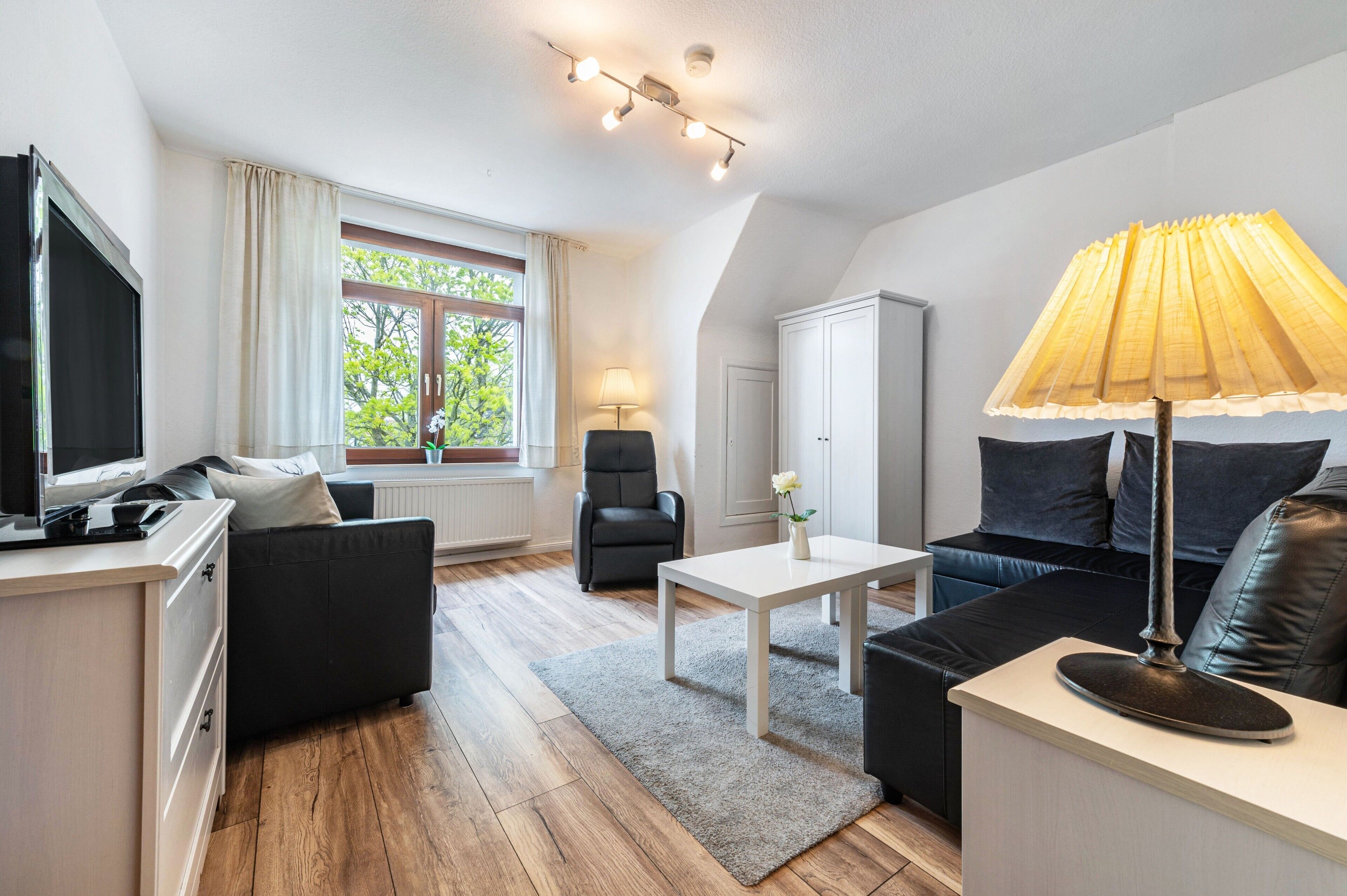 Een moderne woonkamer met een flatscreen televisie, een bank, een salontafel en een lamp.