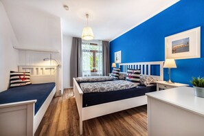 A bedroom with a bed, bedside tables, a desk, a chair, a window with curtains, a hanging light fixture, and a framed picture on the wall. - Apartment '2' with Modern Country-Style Kitchen (Cuxhaven)