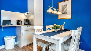 Una cocina compacta con una mesa blanca, sillas y una cafetera.