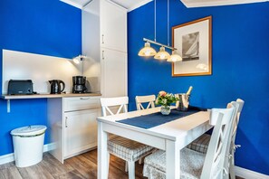 A compact kitchen with a white table, chairs, and a coffee maker. - Apartment '2' with Modern Country-Style Kitchen (Cuxhaven)