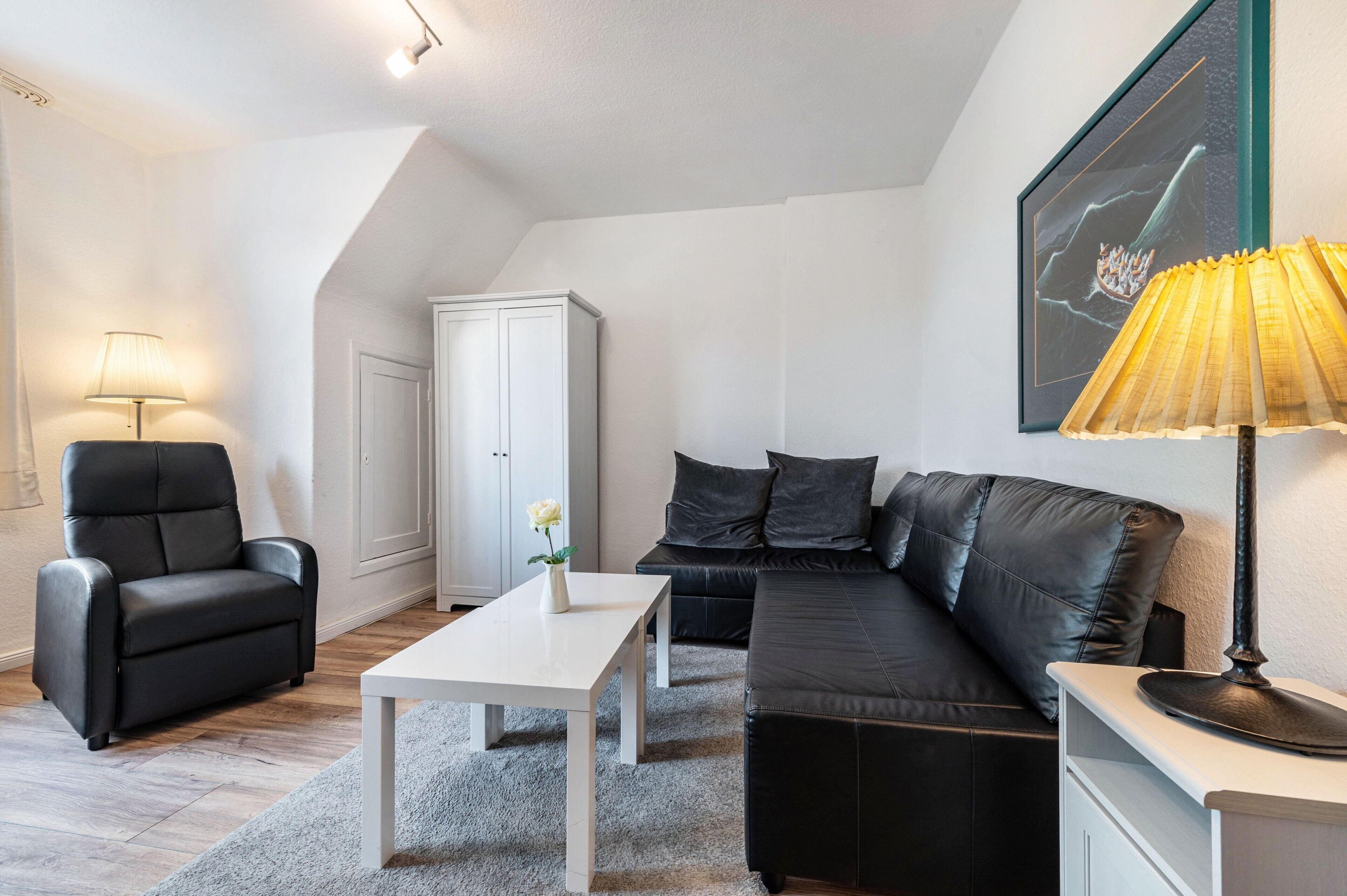 A modern living room with a sofa, armchair, and a table.