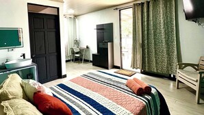 Ein Schlafzimmer mit Bett, Schreibtisch, Stuhl, Fernseher und einer Tür.