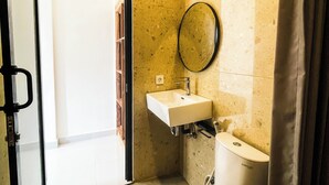 A small bathroom with a toilet, sink, and mirror. - Sundari Guesthouse Pererenan (Pererenan)